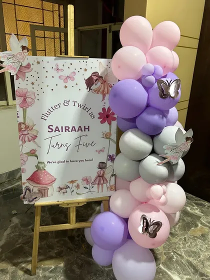 A personalized welcome sign for Sairaah's fifth birthday, decorated with a small balloon garland and fairy-themed graphics. This is the perfect first impression for guests, setting the tone for a magical celebration from the moment they arrive.