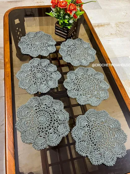 This set of six grey placemats features an intricate, openwork floral design. They are perfect for protecting your table while adding a touch of handmade elegance.