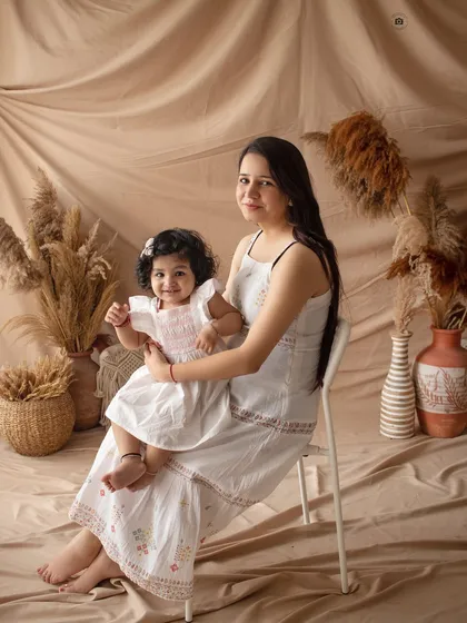 A sweet mother and daughter portrait in our boho studio. The coordinating white outfits and earthy backdrop create a warm and natural feel.