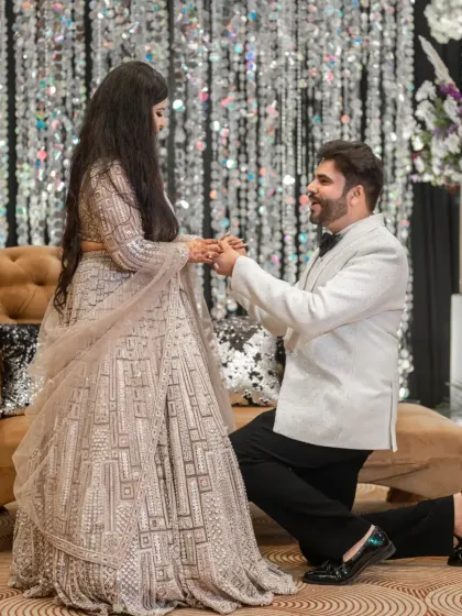 The groom gets down on one knee to propose during the engagement ceremony, a classic romantic gesture.