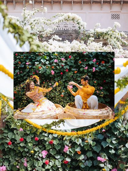 A playful shot of the couple sitting in large brass pots, showering each other with flower petals.