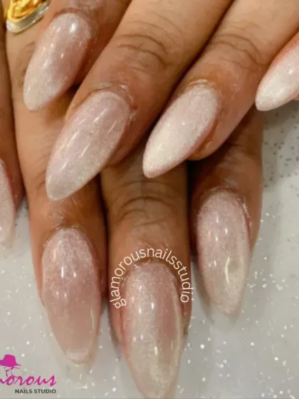 A simple and elegant look with a pearlescent finish. These long, almond-shaped nails have a beautiful, shimmery white coating that gives them a "glazed donut" effect, perfect for a clean and trendy style.