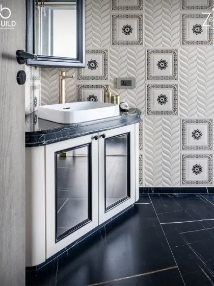 A bathroom from 'The House of Arcs' featuring patterned wall tiles and a black marble floor. The custom vanity with black and white details adds a classic touch.