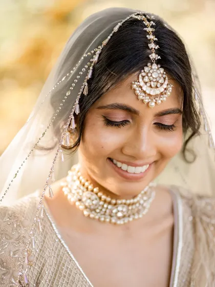 A close-up of the bride's radiant smile. Her minimalist makeup and elegant pearl and polki choker from Purab Paschim perfectly complemented her ivory Tarun Tahiliani wedding lehenga.