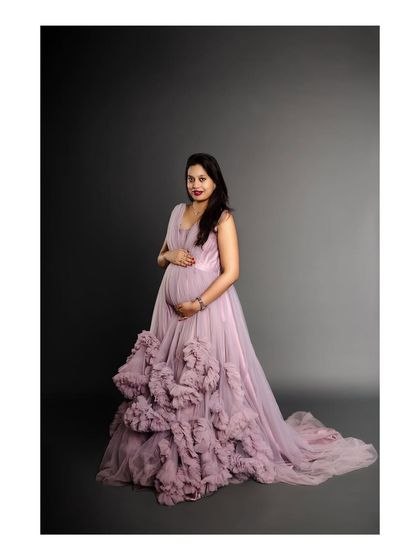 A full-length portrait of an expectant mother in a magnificent lavender gown. This studio shot highlights the intricate details and grand scale of our styled maternity sessions.