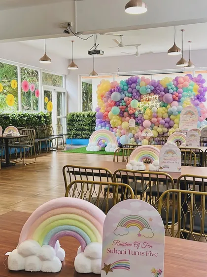 A wide view of the restaurant space transformed for Suhani's rainbow birthday. The massive balloon wall served as the focal point, with rainbow centerpieces on each table to continue the theme.