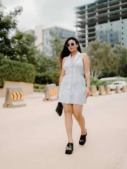 A full-length shot of a model walking in a stylish dress. The urban background and her confident stride create a classic fashion-on-the-move image.