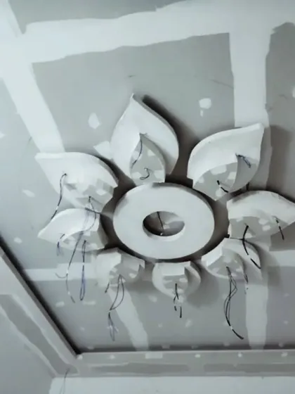 The raw form of a flower-petal design taking shape on the ceiling. The wiring shows preparations for a central chandelier and surrounding spotlights.