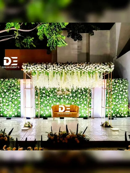 An evening reception calls for a special kind of magic. I designed this stage with a lush green floral wall, a canopy of cascading white wisterias, and elegant gold frames, all expertly lit to create a warm, sophisticated, and glamorous atmosphere after dark.