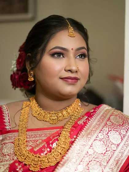 A close-up of a bride's classic look, featuring bold eyes and traditional gold temple jewelry.