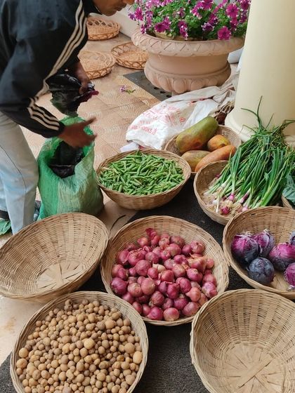 A farmer's stall with baskets of potatoes, onions, beans, and papaya.