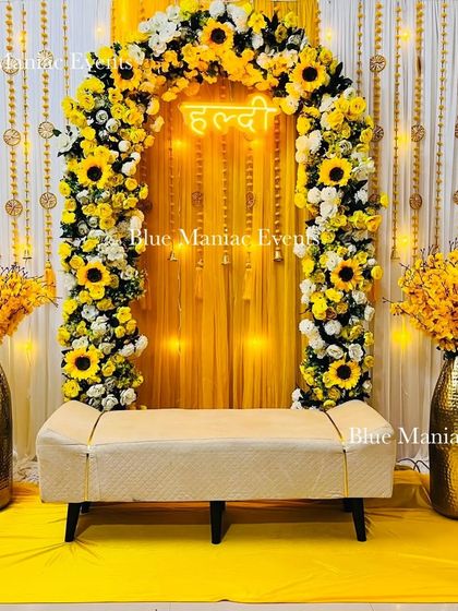 Another view of the sunflower Haldi setup, showing the elegant bench seating and the tall golden vases filled with yellow flowers.