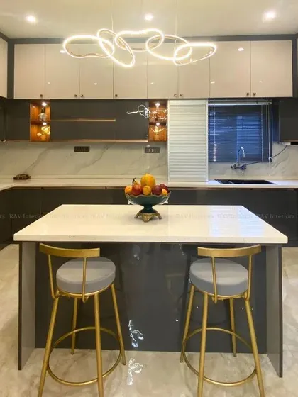 We designed this modern U-shaped modular kitchen to be both a chef's delight and a family hub. It features a sleek island that doubles as a breakfast counter, high-gloss grey and white cabinets for ample storage, and a stunning designer chandelier that adds a touch of luxury.