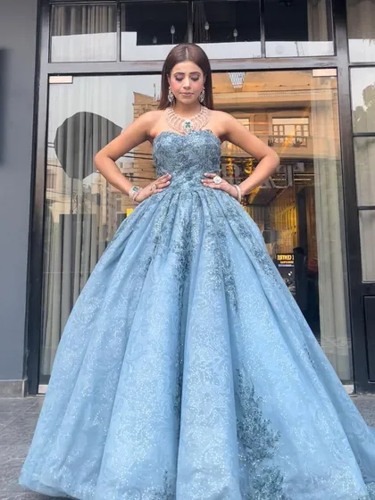 A powerful front view of our dusty blue princess ball gown. The strapless, embellished bodice and the voluminous, embroidered skirt create a stunning and timeless silhouette.