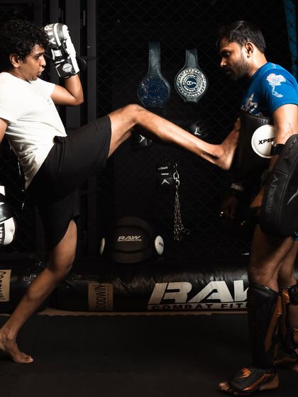A fighter practices a front kick on the pads, a key technique for maintaining distance.