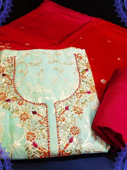 A stunning light blue dress material with a contrasting red Banarasi dupatta. The top features delicate embroidery, making it a perfect blend of simplicity and richness.