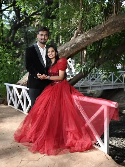 A classic pre-wedding pose on a picturesque bridge. The full red ball gown adds a wonderful splash of color to the natural surroundings.