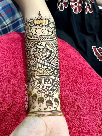 A close-up of the forearm detail for a bridal henna, featuring engagement rings and a lotus.
