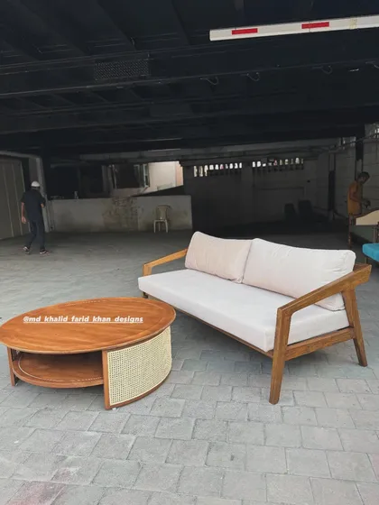 A living room set featuring a minimalist sofa and a round coffee table with a caned lower shelf.