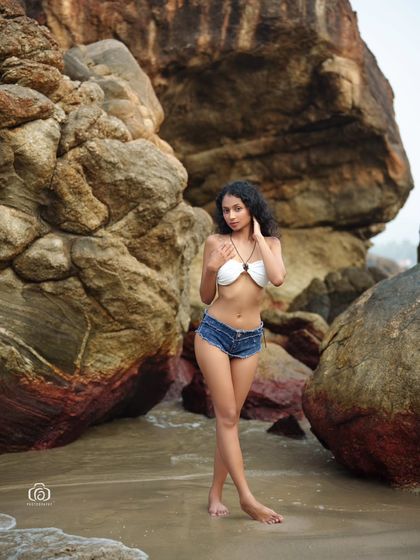 A classic beach portrait with the model posing against the unique rock formations of the Goan coast. The natural light and setting create a timeless and beautiful image.