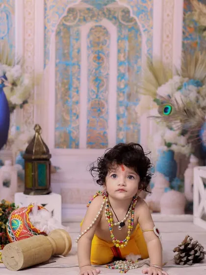 This little one looks up with wide, curious eyes, dressed as Krishna and surrounded by festive decor. A perfect shot capturing the wonder of childhood.