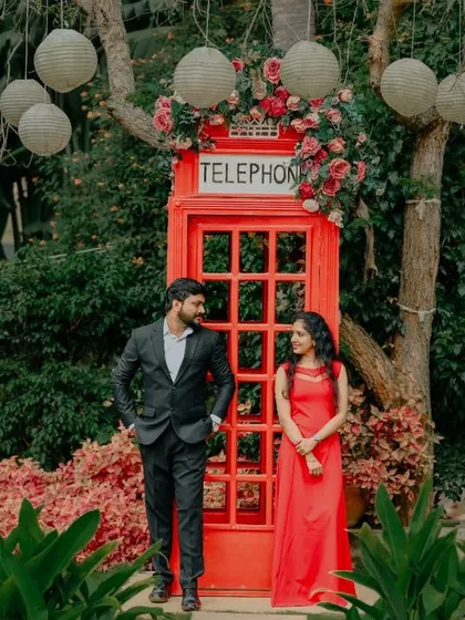 The red telephone booth, adorned with flowers, provides a whimsical and charming backdrop for a couple's portrait.