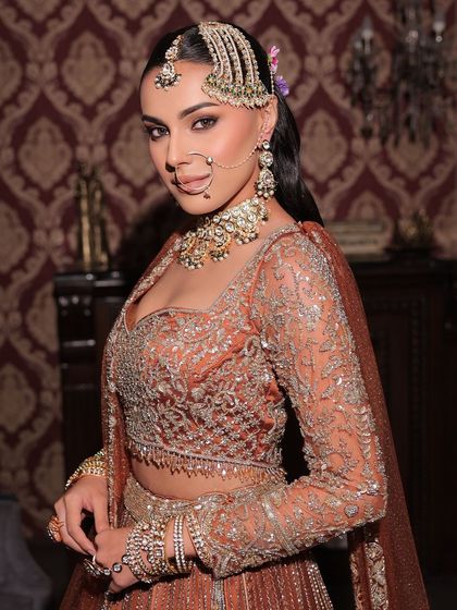 A beautiful portrait of a guest in a stunning rust-colored outfit. The makeup is warm and glowing, enhancing her natural beauty.