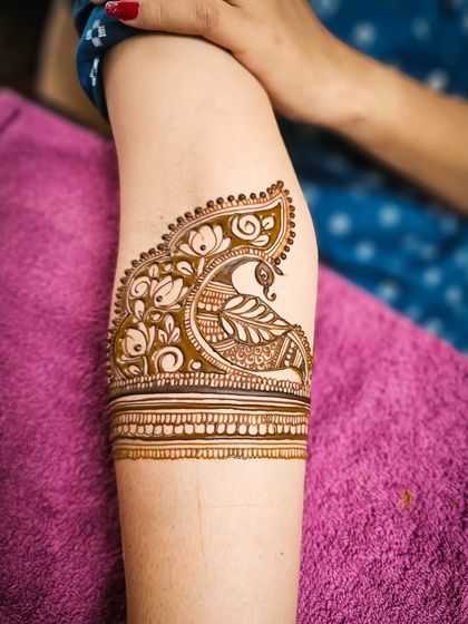 A close-up of a beautiful peacock armband, a classic and graceful element in bridal henna.