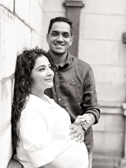 A beautiful black and white couple portrait against a simple architectural background. The image has a classic, elegant feel, focusing on their hopeful expressions and gentle interaction.