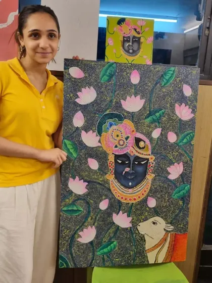 A student proudly displays her large, intricate Pichwai-style painting of Lord Krishna, a beautiful piece she created in my class.