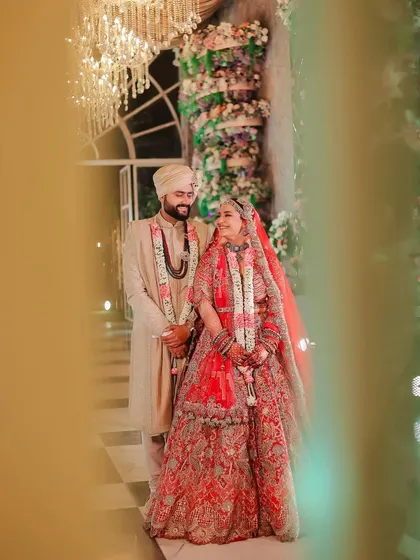 A candid, through-the-foliage shot of the couple sharing a smile during their wedding. This artistic framing adds depth and a sense of intimacy to the moment.