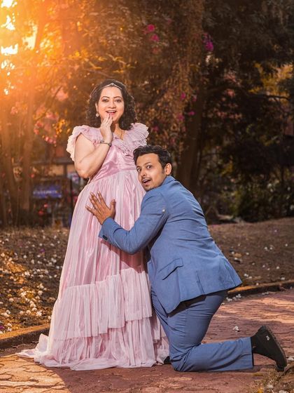 A fun and candid moment from an outdoor session. The dad-to-be's playful pose contrasts beautifully with the soft, romantic feel of the pink gown and the golden hour light.