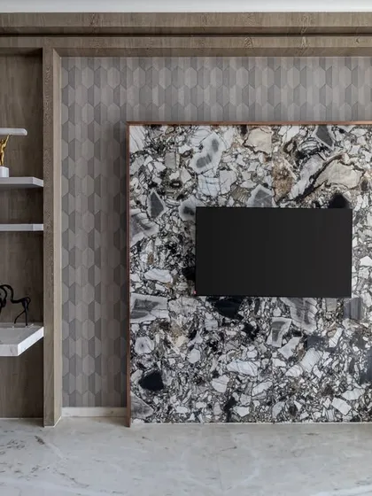 A unique TV unit design where the screen is mounted on a stunning slab of patterned marble, turning it into a piece of art. The adjoining floating desk creates a compact and stylish workspace.
