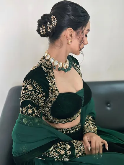 A side profile showing the elegant braided bun hairstyle, adorned with delicate golden leaf accessories.