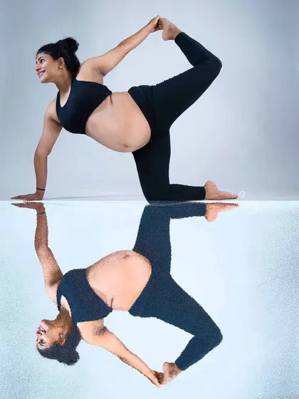 A playful and creative reflection shot. This image captures a mom-to-be doing a yoga pose, with her reflection creating a perfectly symmetrical and visually interesting portrait.
