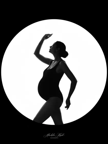 A fine art silhouette captured within a circle of light. This artistic approach creates a dramatic and memorable portrait that celebrates the beautiful shape of pregnancy.