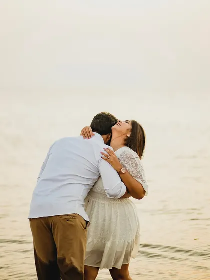 A moment of pure, uninhibited joy as the couple shares a laugh and a hug on the beach. This candid shot perfectly captures the fun and happiness of their relationship.