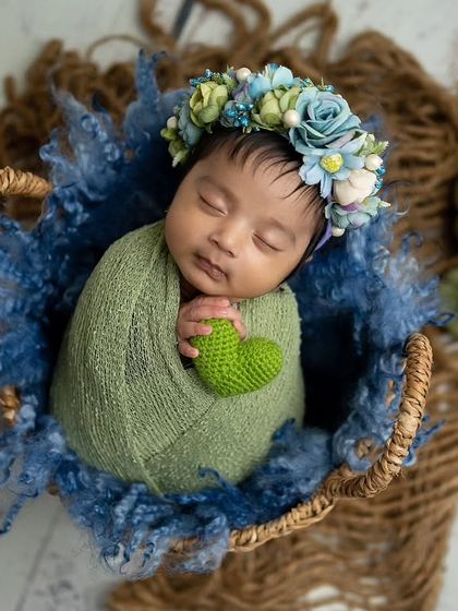 A lovely combination of green and blue. The baby is wrapped in a green swaddle, placed in a basket with blue textured fabric and cute pumpkin props.