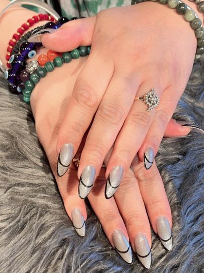 A sleek and modern design on stiletto nails, featuring a silver base with clean, curved black lines.