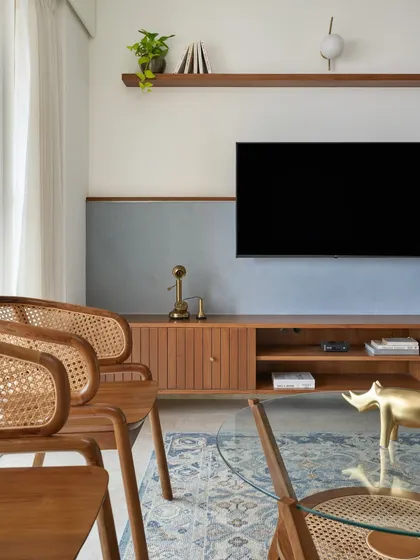 A close-up of the 'Malhar' TV unit, featuring a sleek veneered design and a textured half-wall. The combination of rattan, wood, and color creates a contemporary classical theme.