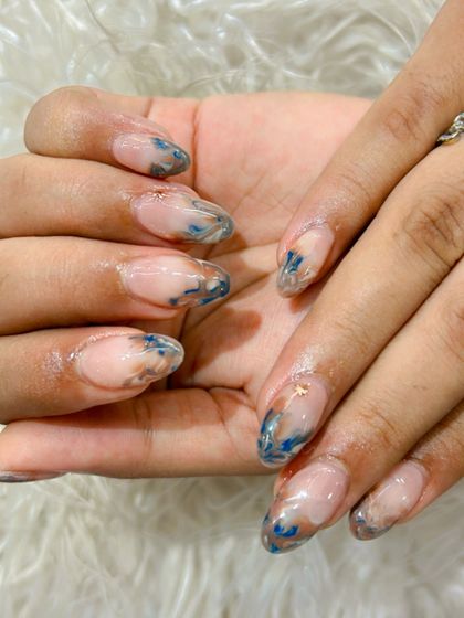 This abstract design features a beautiful marble effect with swirls of blue, brown, and gold on a translucent base. It's a modern and artistic take on nail extensions.