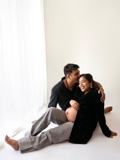 A sweet kiss on the cheek. This is a more intimate and quiet moment from their candid maternity shoot, showing the deep affection between them.