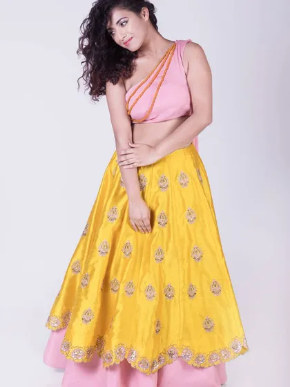 For me, clothes are about celebrating our many moods. This vibrant set features a one-shoulder pink crop top with a bright yellow skirt that has delicate buti embroidery. It’s a fun, fresh, and playful Indo-western outfit perfect for a sangeet or daytime event.