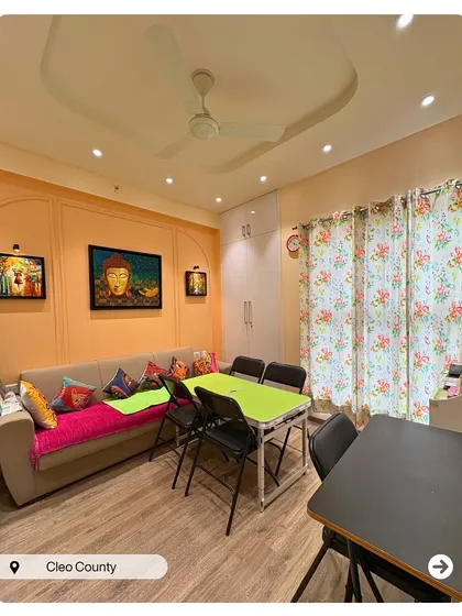 A multifunctional living and dining space in Cleo County. The design uses a consistent color palette and wooden flooring to unify the area while accommodating different activities.