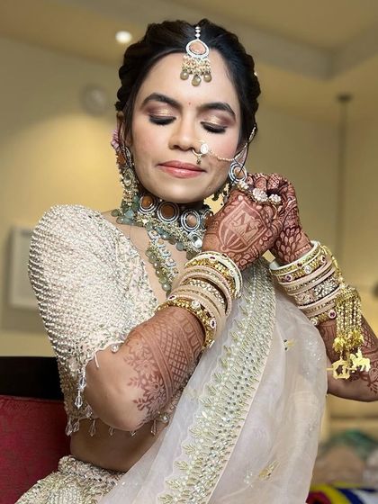 A serene moment as the bride puts on her earrings, showing off her beautiful hairstyle.