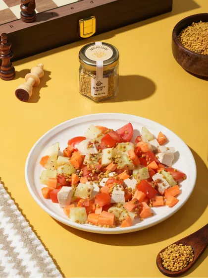 A healthy salad topped with bee pollen, styled with a chess set for a sophisticated lifestyle feel. This shows how we can integrate food products into broader lifestyle concepts.