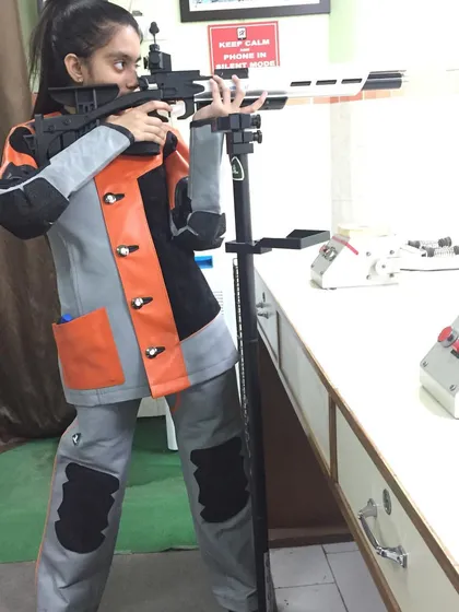 A student practicing with her air rifle, using a stand to ensure stability and perfect her aim.