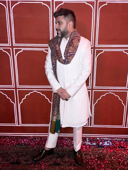 An elegant Diwali look featuring a white bandhgala paired with a luxurious pashmina shawl, demonstrating how to layer accessories for a sophisticated festive outfit.