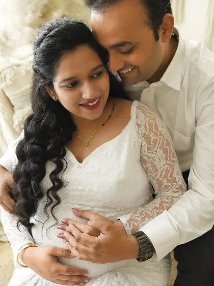 A tender moment captured during a bright and airy maternity session. The white lace dress and the husband's embrace create a feeling of pure love and happiness.