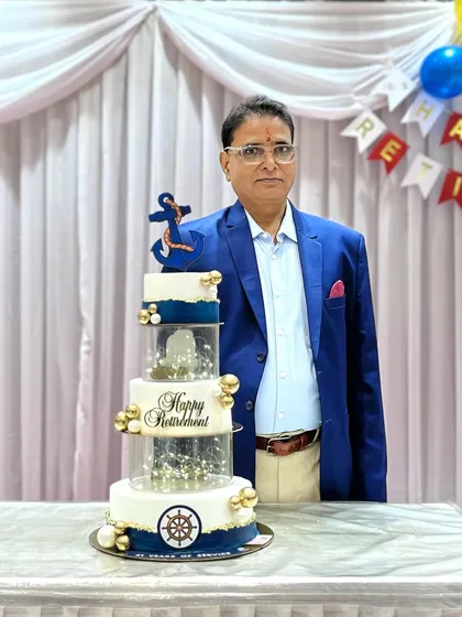 A proud moment for the retiree, standing next to the cake that celebrates his years of service.